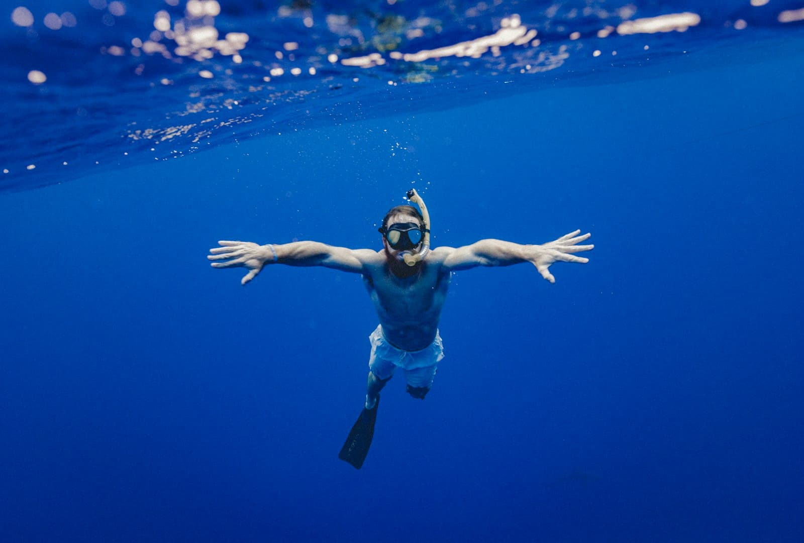 A swimmer in clear water seen from above, the bottom visible